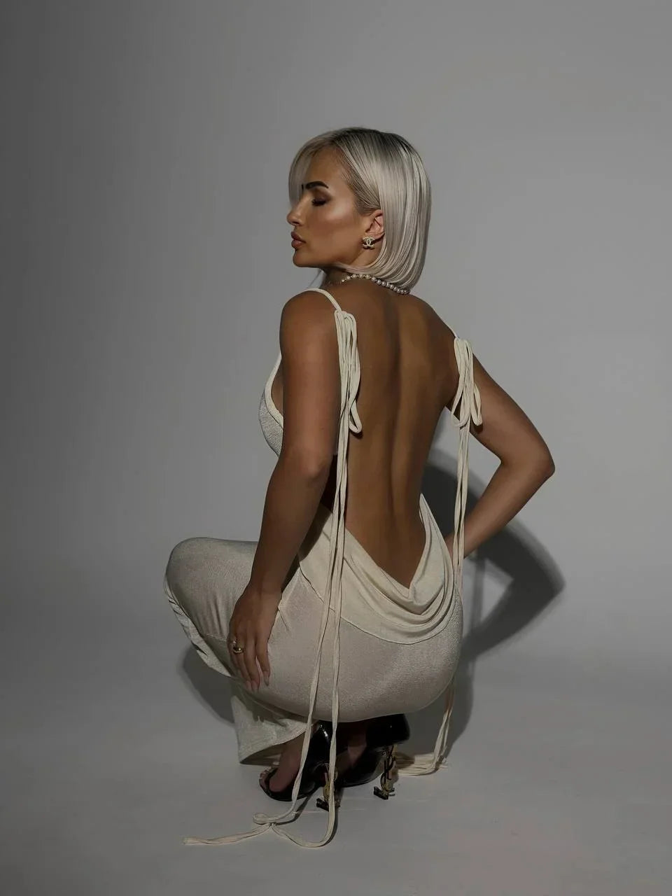 White women's backless maxi dress featuring adjustable ties and lightweight fabric, perfect for warm weather outings.