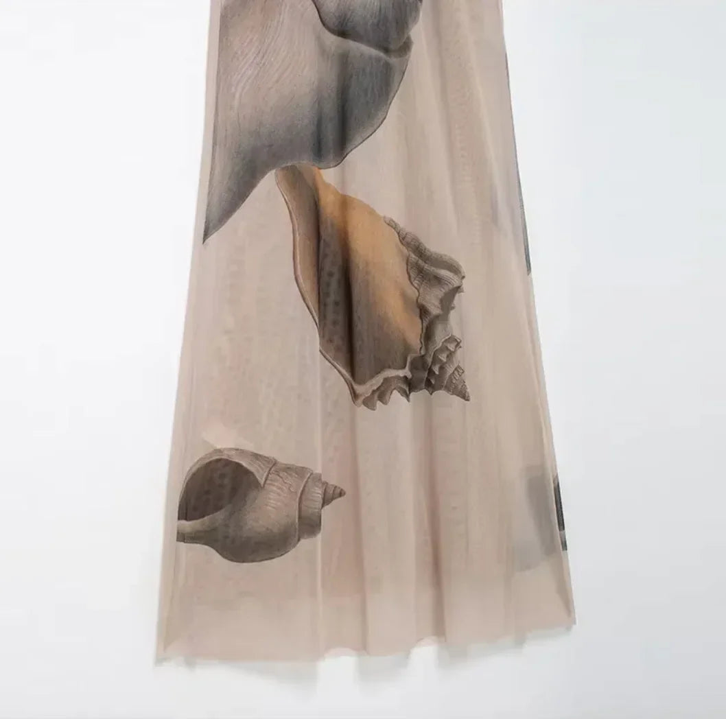 Elegant halter maxi dress in beige with shell print, featuring a flowing design made from lightweight, breathable fabric.