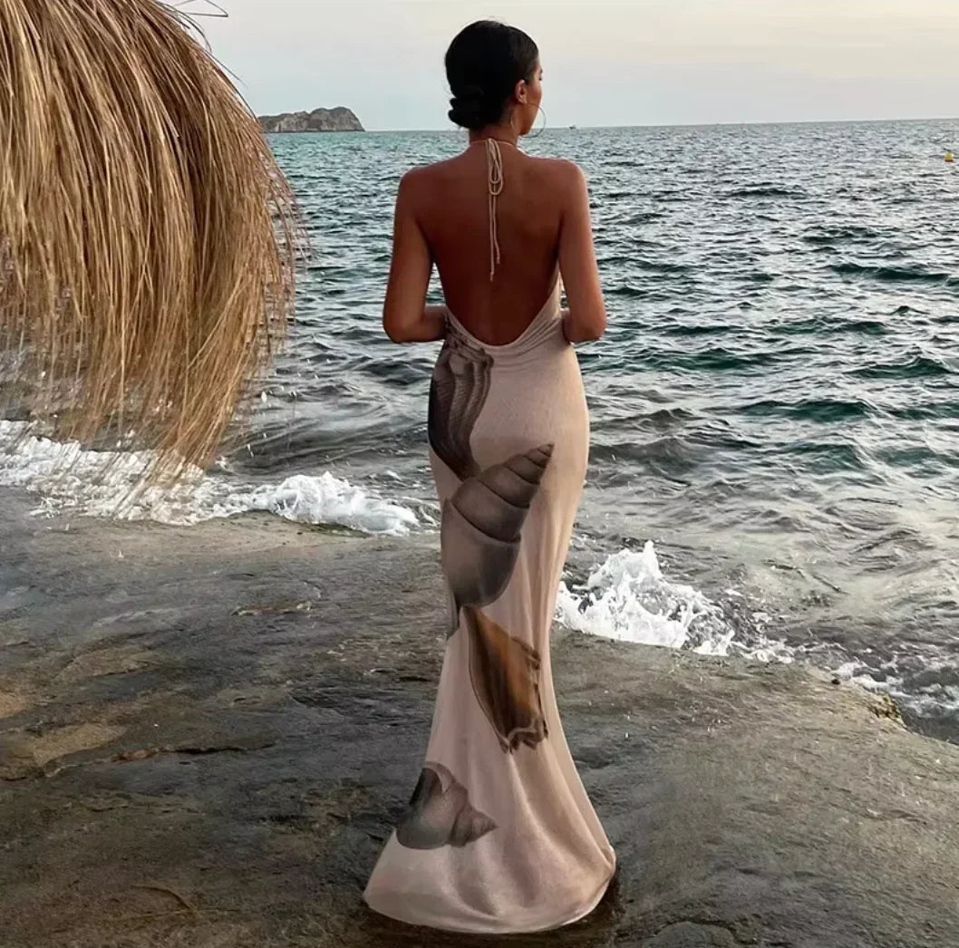 Women’s beige shell print halter maxi dress made of lightweight fabric, featuring a flowing design and elegant shell pattern.