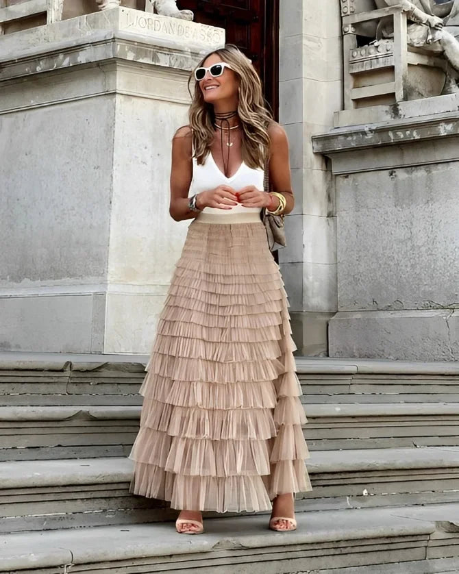 Women's beige tiered maxi skirt paired with a white sleeveless top, featuring lightweight fabric and a flowing silhouette.