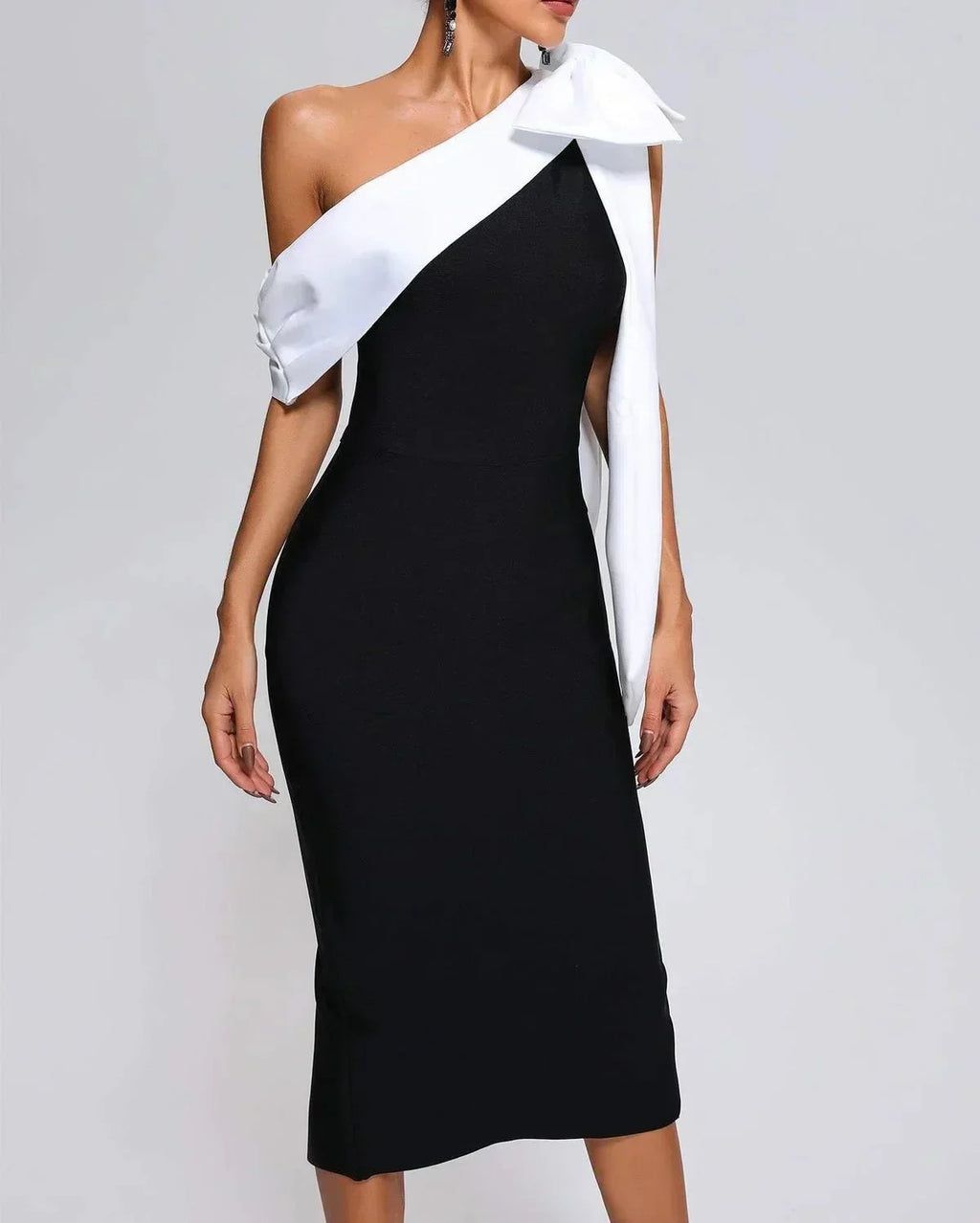 Women’s black and white one-shoulder midi dress made from soft fabric, featuring a stylish bow accent and asymmetrical…