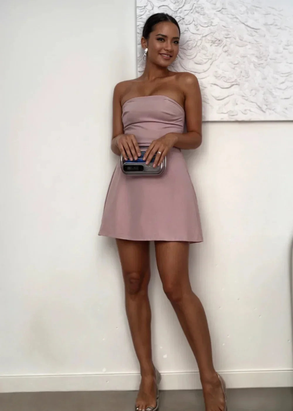 Women’s blush strapless mini dress in soft fabric with a fitted bodice, paired with a matching clutch for a coordinated look.