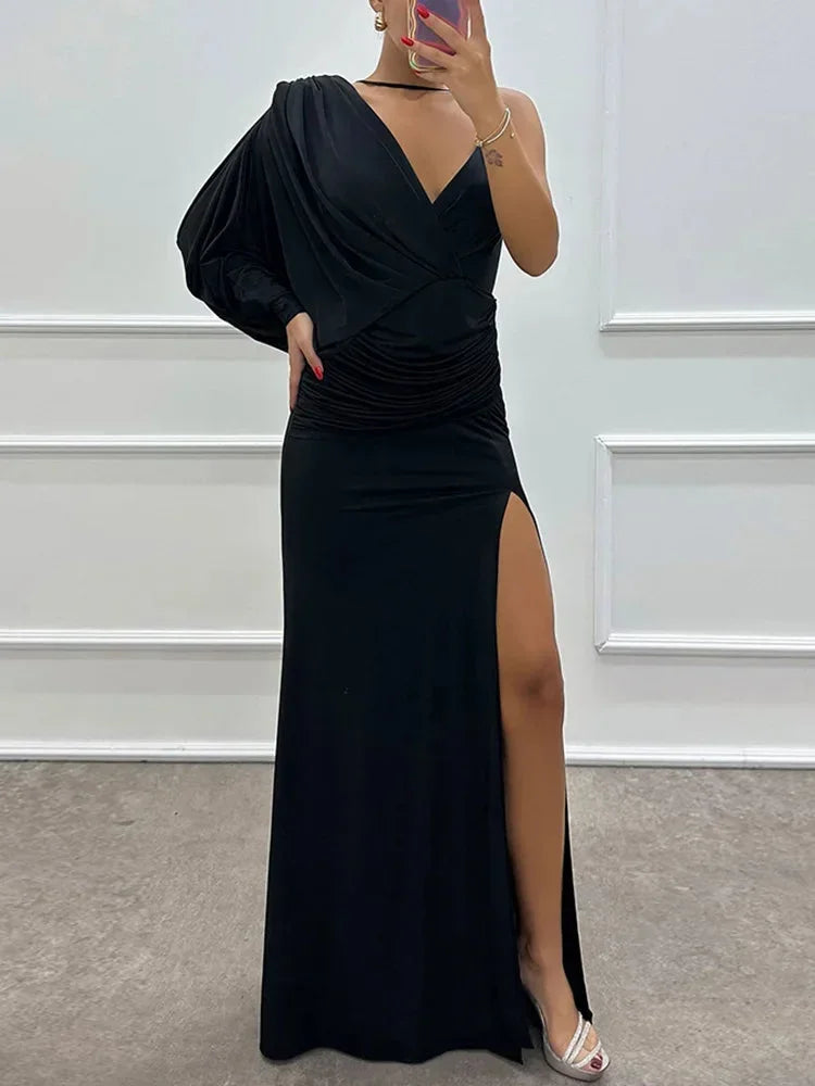 Black one-shoulder maxi dress with draped design, side slit, and soft fabric for a comfortable fit and elegant silhouette.