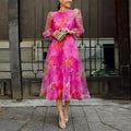 Pink women's midi dress featuring a floral print, sheer puff sleeves, and lightweight fabric for a comfortable fit.