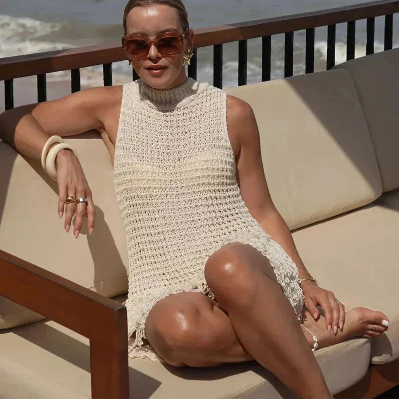 Women’s ivory sleeveless mini dress made of lightweight fabric, featuring playful tassel accents along the hem and neckline.