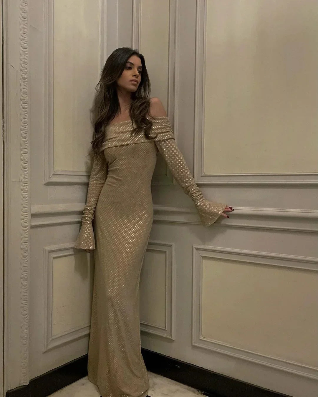 Beige off-shoulder maxi dress with glitter, flare sleeves, and a flowing silhouette, perfect for special occasions.