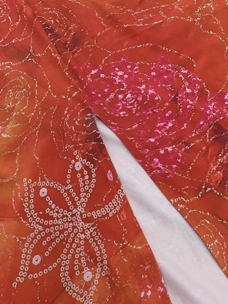 Women’s orange floral halter neck maxi dress made of sheer fabric with a flowy silhouette and vibrant flower patterns.