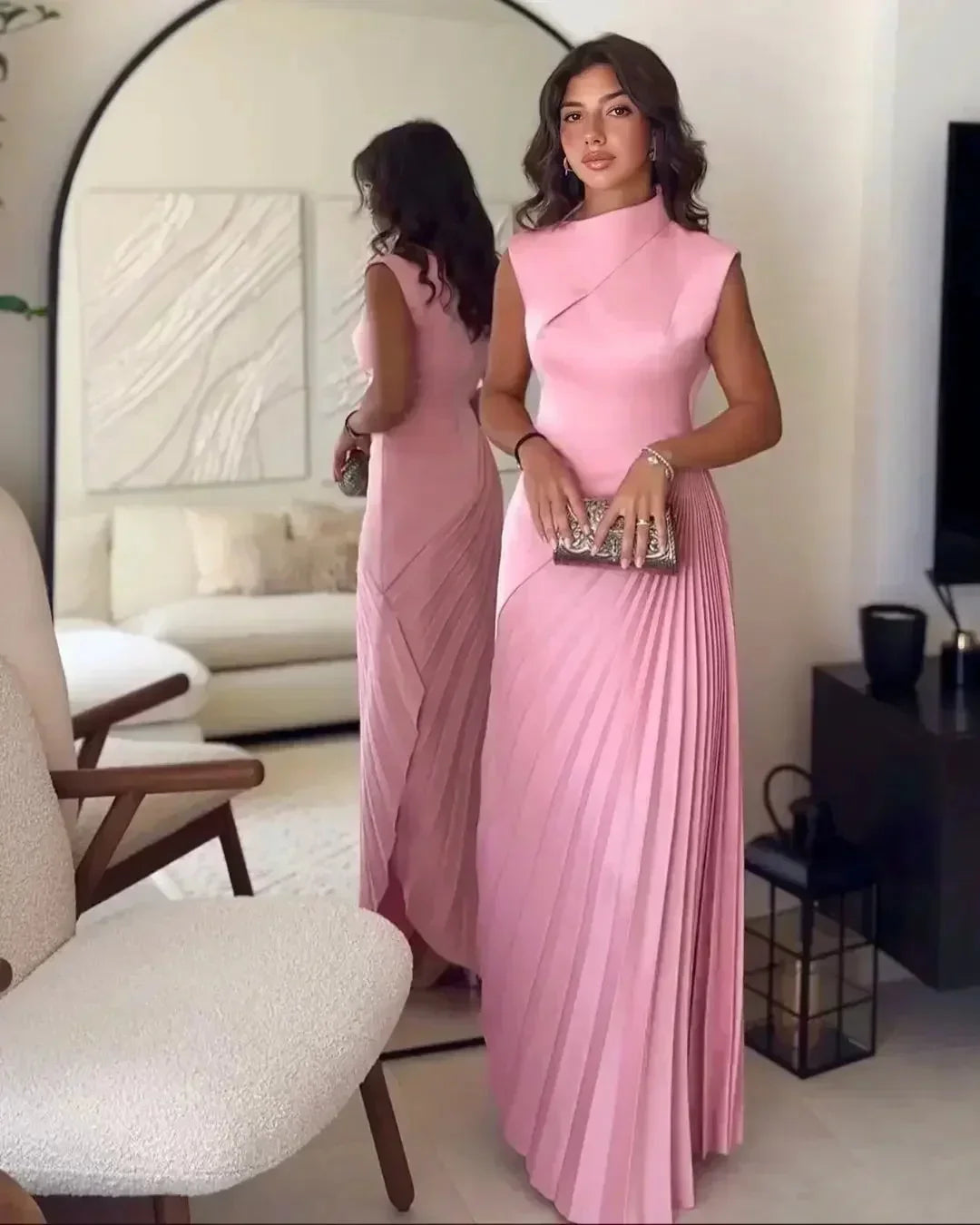 Women's pink pleated sleeveless maxi dress featuring an asymmetrical neckline and soft, lightweight fabric.