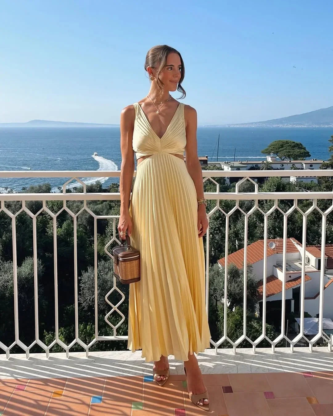 Women’s yellow maxi dress featuring pleats, cut-out detail, and a plunging neckline, crafted from lightweight, flowy fabric.