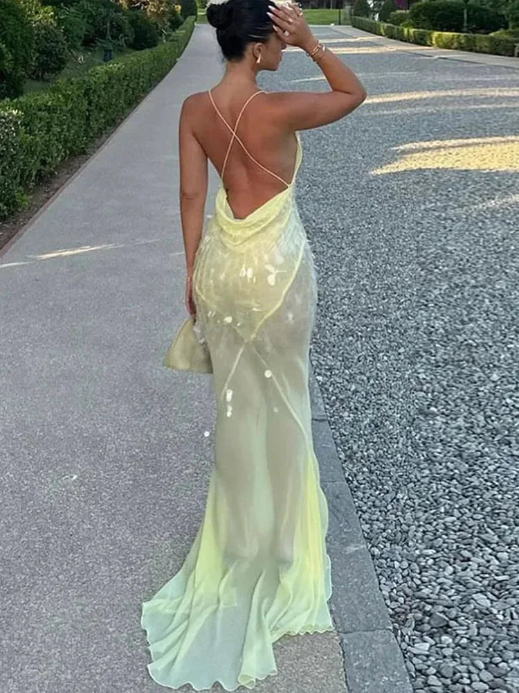 Women’s sheer yellow backless maxi dress featuring sequins, lightweight fabric, flowy design, and elegant backless…