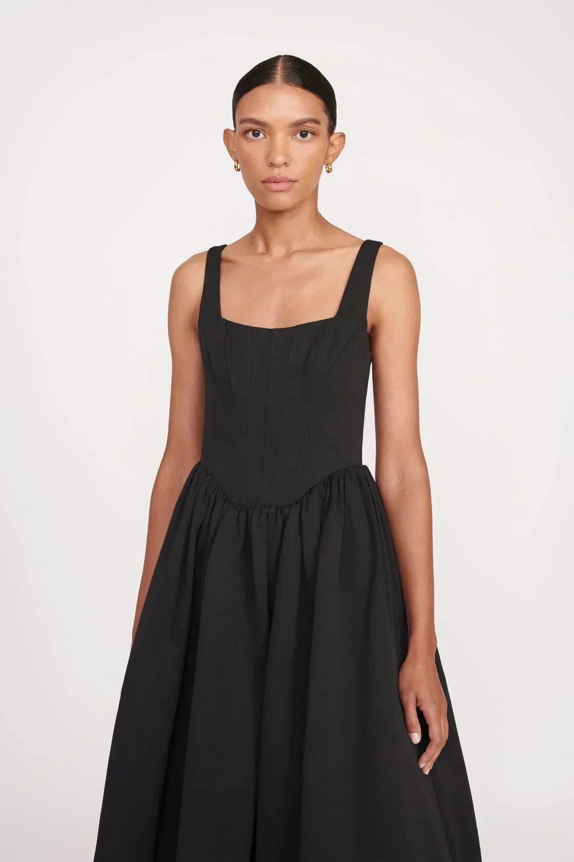 Women’s sleeveless black maxi dress with square neckline, made of soft fabric, featuring a flared skirt for fluid movement.