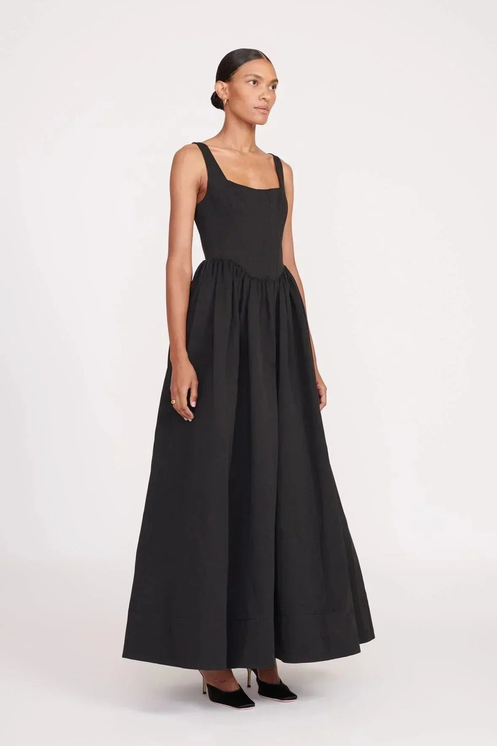 Women's sleeveless black maxi dress with square neckline, flared skirt design, made from lightweight cotton blend fabric.