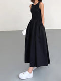 Black sleeveless jersey midi dress featuring a flowing skirt, designed for comfort and ease of movement. Perfect for warm…