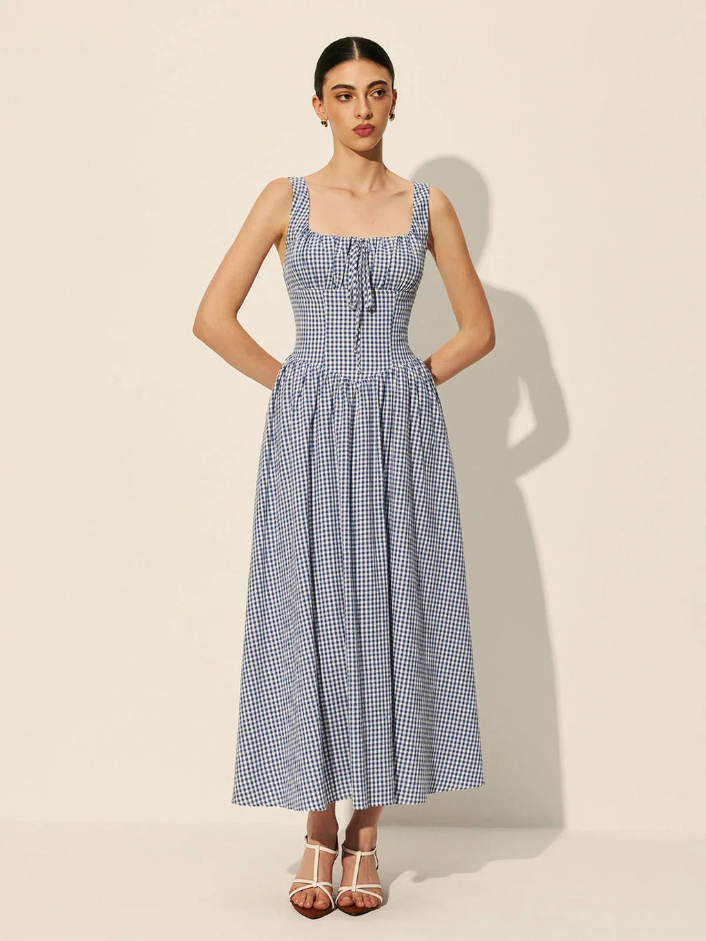 Women’s sleeveless navy gingham midi dress featuring a square neckline and lightweight fabric for comfort and style.