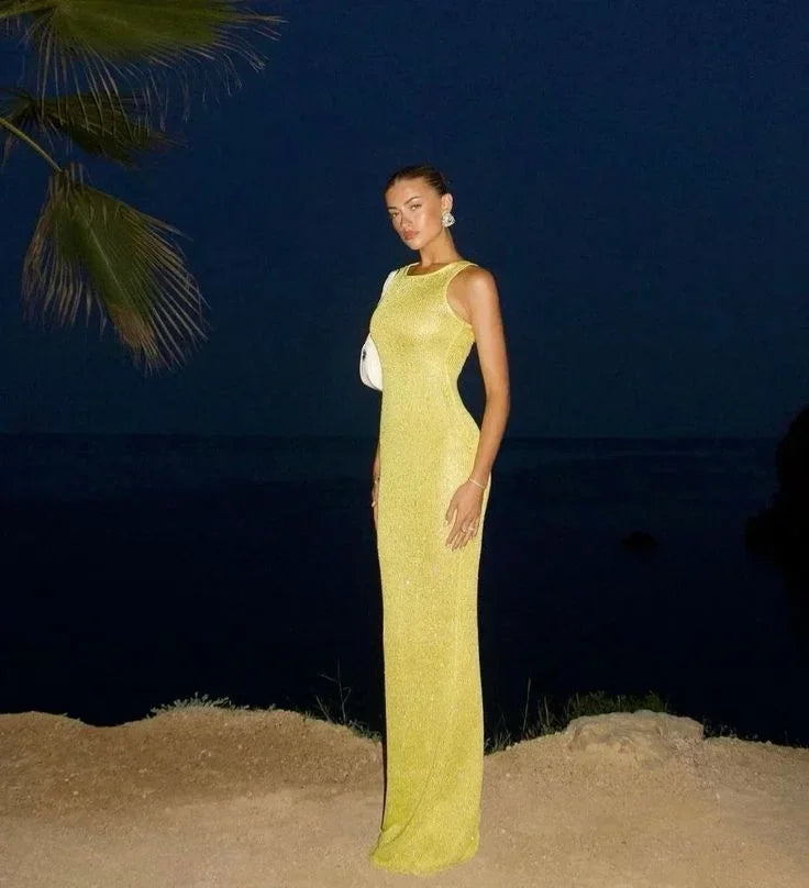 Women’s sleeveless fitted maxi dress in shimmering fabric, featuring a form-fitting silhouette and elegant floor-length…