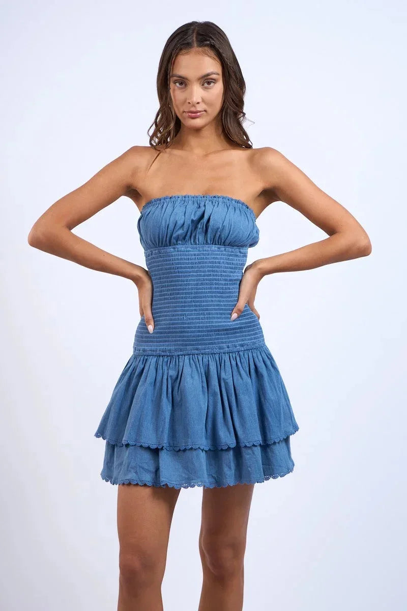 Denim blue strapless mini dress with smocked bodice and tiered layers, perfect for casual outings or summer events.