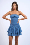 Denim blue strapless mini dress with smocked bodice and tiered layers, perfect for casual outings or summer events.